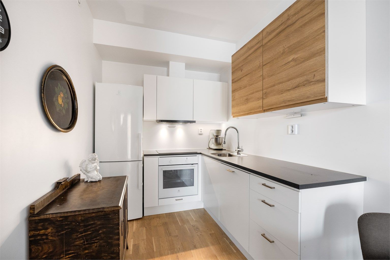 Kjøkkenet har en praktisk utforming med integrert komfyr, induksjonstopp og oppvaskmaskin.