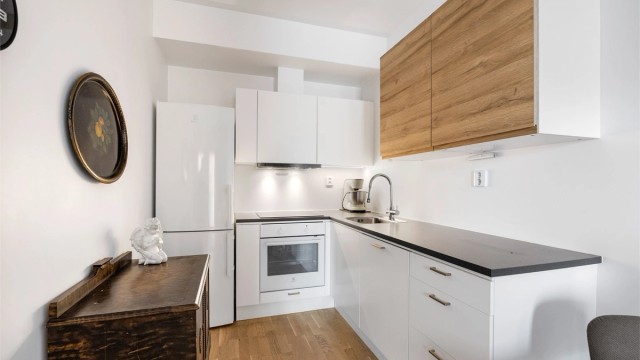 Kjøkkenet har en praktisk utforming med integrert komfyr, induksjonstopp og oppvaskmaskin.