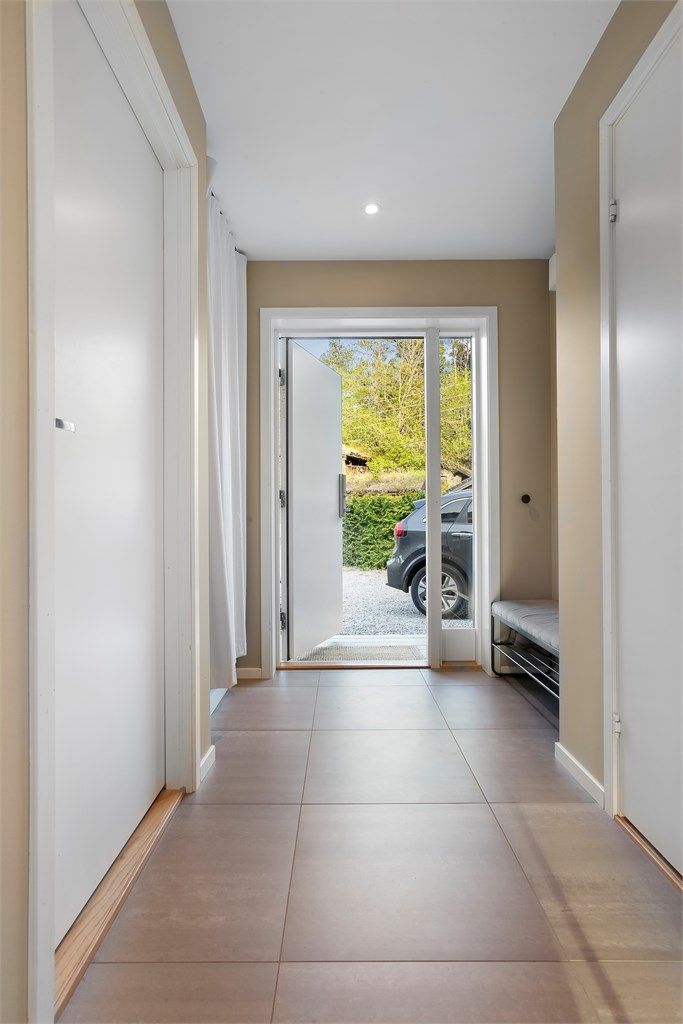 Entréen har store, lysegrå 60x60 cm fliser med varmekabler og innfelte downlights i taket.