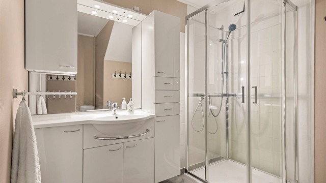 Badet er enkelt og er utstyrt med servant, innredning, wc og dusjkabinett.