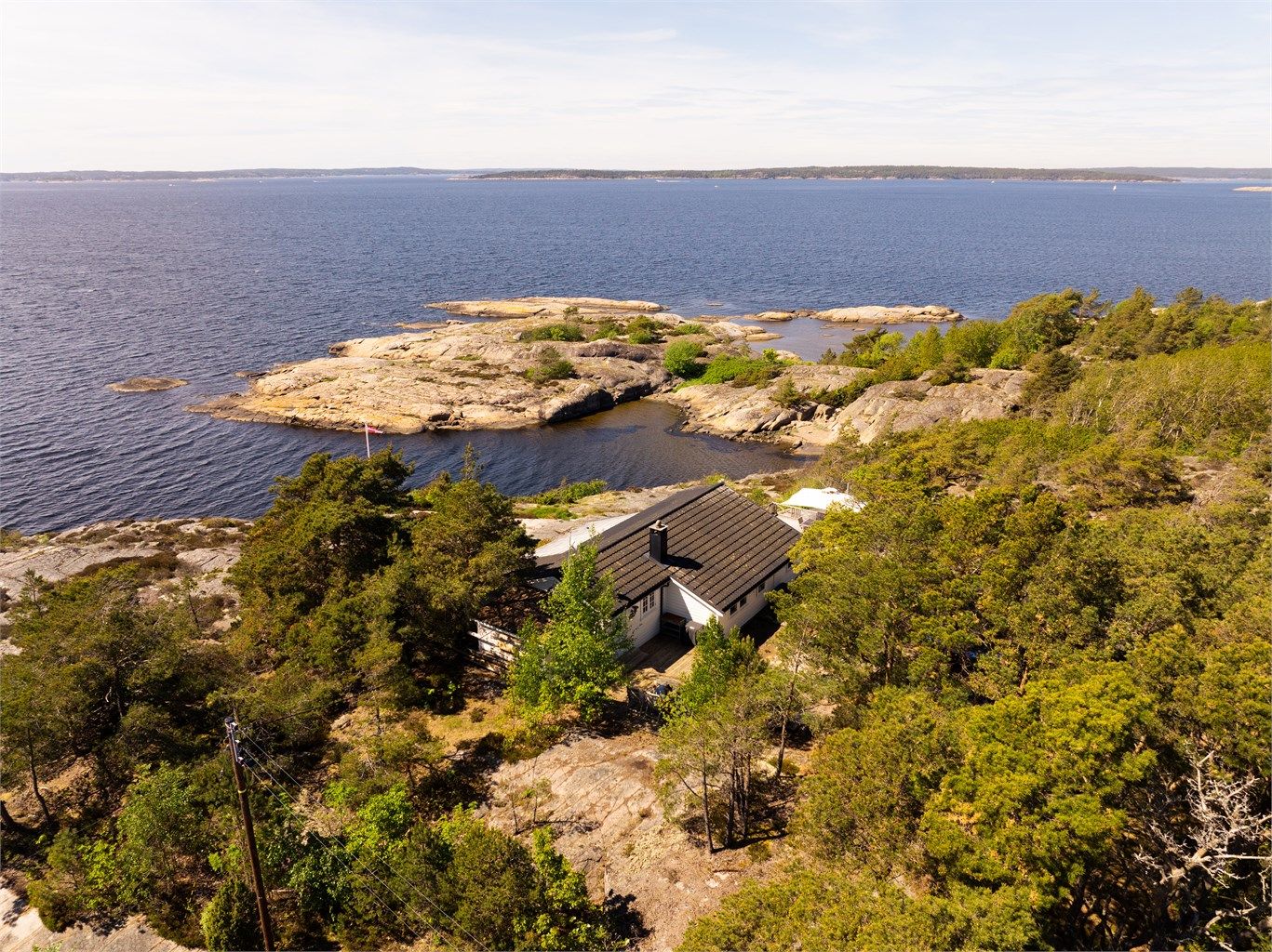 Den romslige tomten er hovedsakelig frittliggende, med en delvis tilstøtende naboeiendom bak skogholtet i øst.