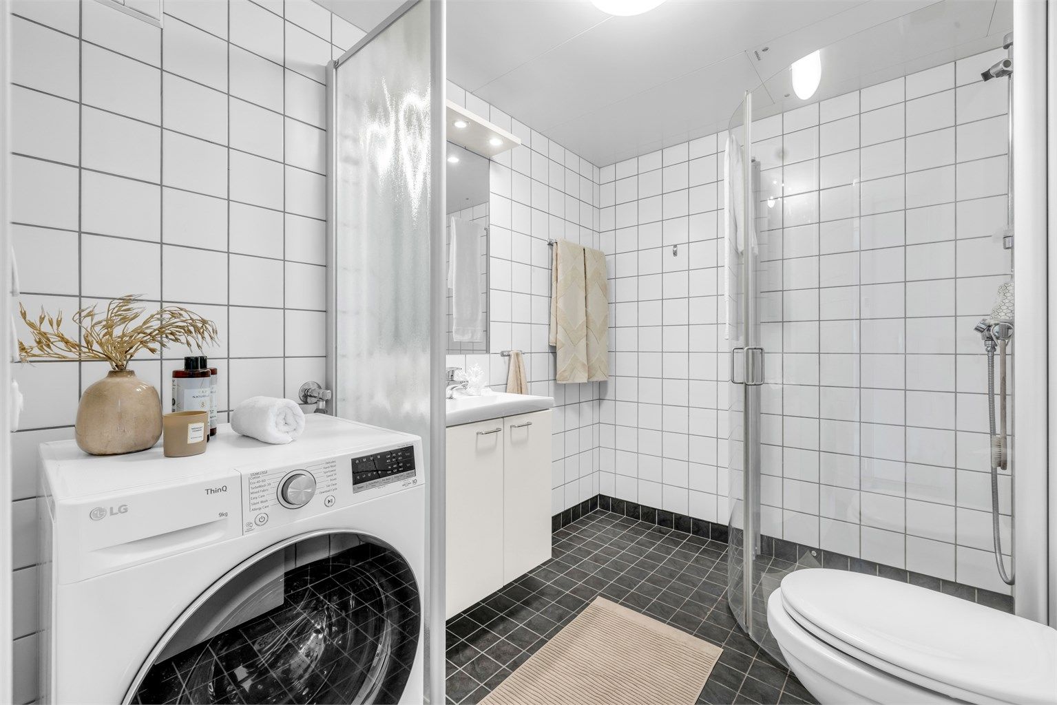 Badet er flislagt med varmekabler i gulv for en behagelig start på dagen og takplater i himling. Her er det opplegg for vaskemaskin.
