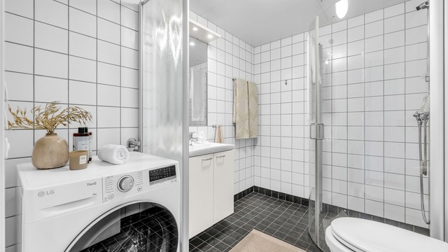 Badet er flislagt med varmekabler i gulv for en behagelig start på dagen og takplater i himling. Her er det opplegg for vaskemaskin.