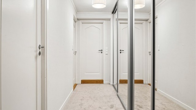 Gang med skyvedørsgarderobe som har speilfronter
