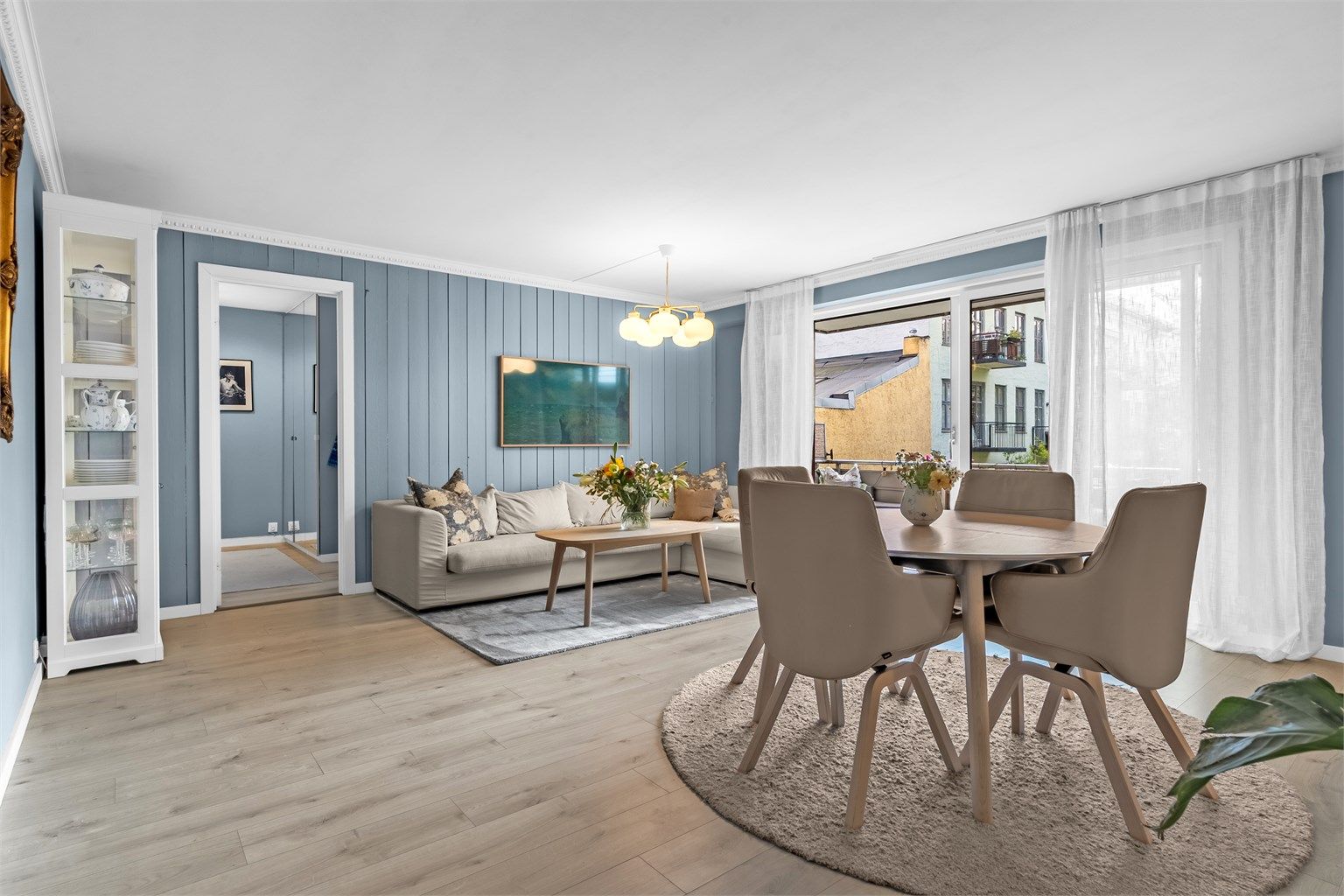 Stuen har store vindusflater fra gulv til tak, som slipper inn rikelig med naturlig lys og skaper en luftig romfølelse.