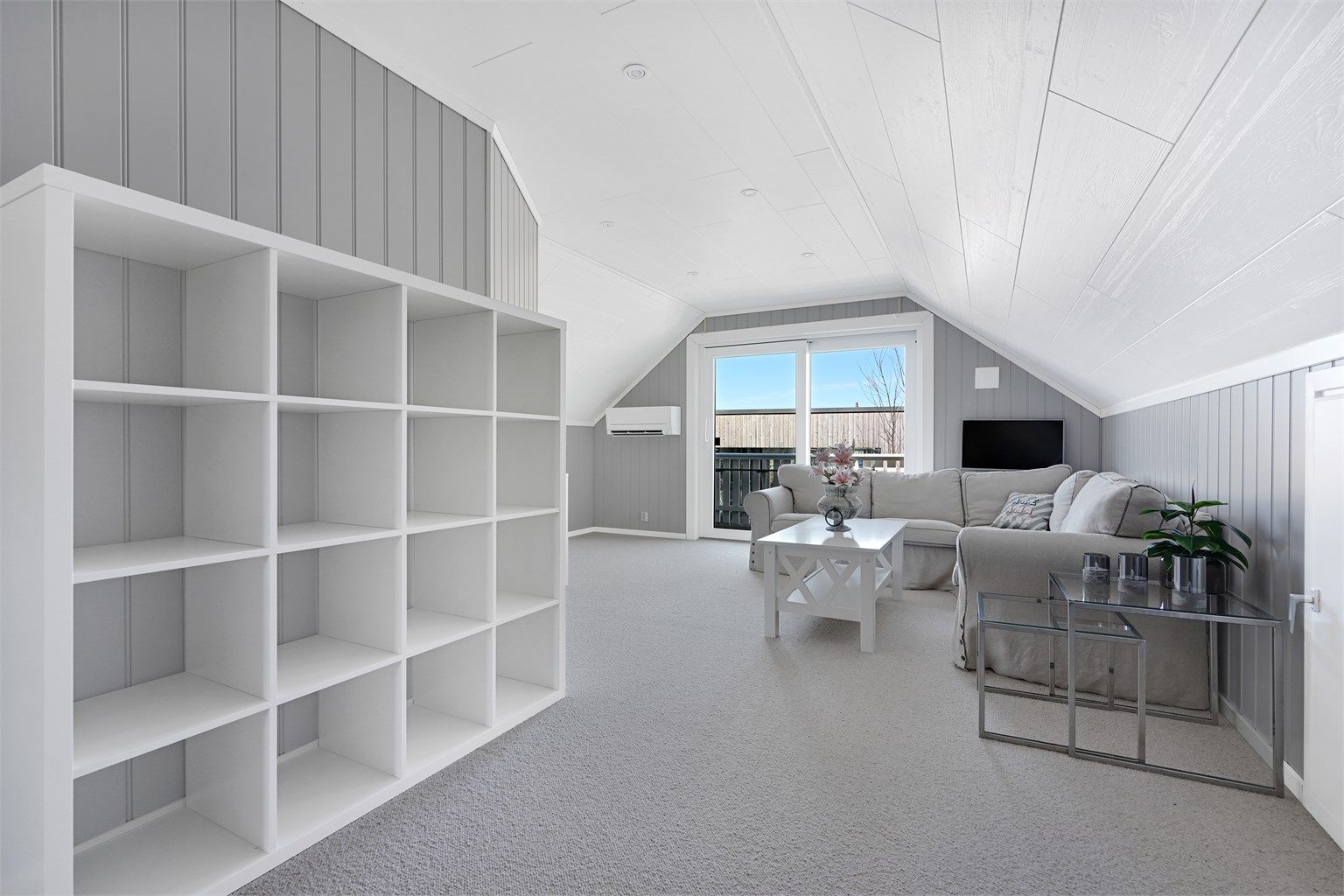 Den romslige loftstuen har heldekkende teppe på gulvet og utgang til balkong via skyvedør.