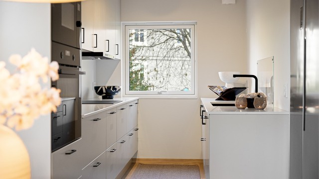 Kjøkkeninnredning fra 2025 med glatte fronter og benkeplater av stein.