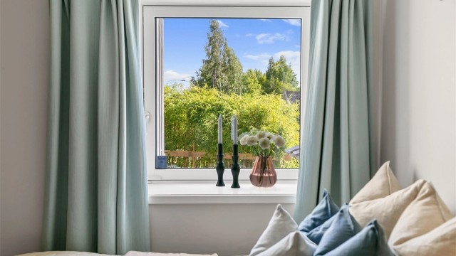 Vinduet vender ut mot frodig vegetasjon i hagen.