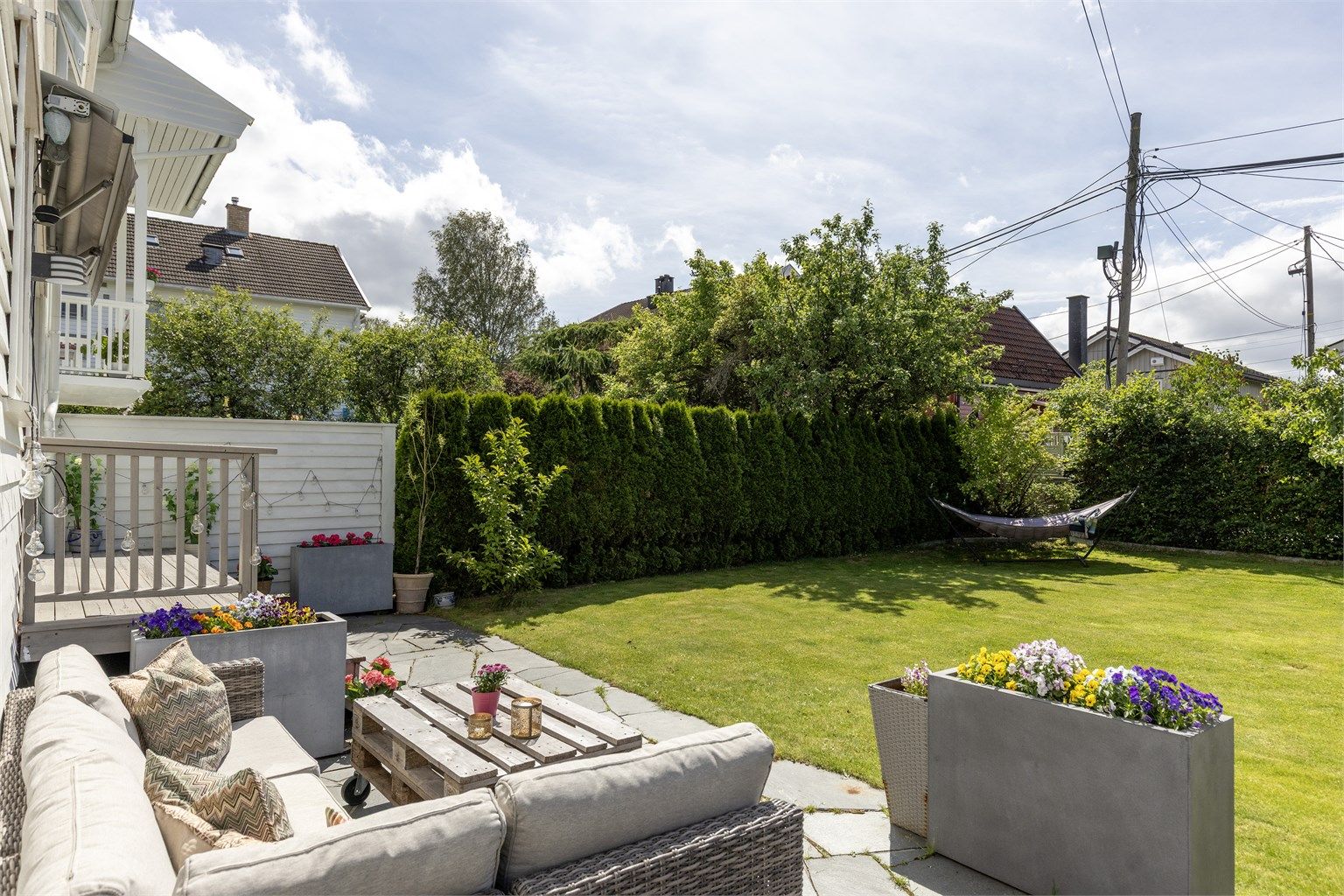 Det er montert markise over trappen ned til hagen. Sommerbilder tatt i 2025 for å illustrere hvordan eiendommen ser ut på sommeren.