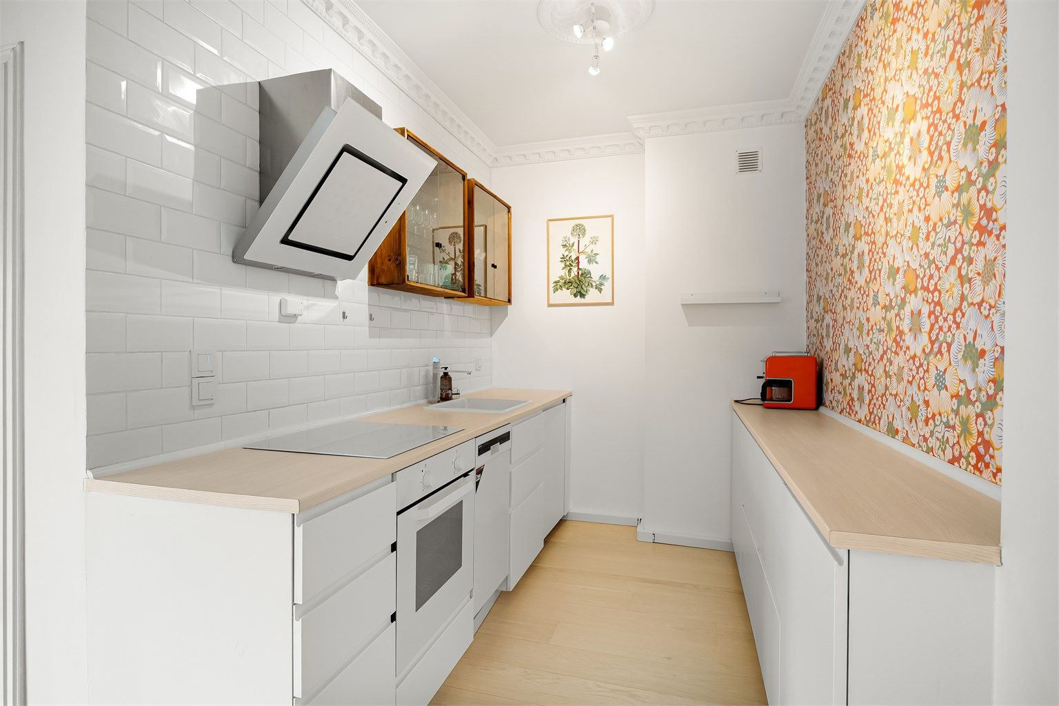 Hyggelig kjøkken som er innredet med glatte skapfronter og benkeplate i laminat med trestruktur og nedfelt kjøkkenvask i benkeplaten.