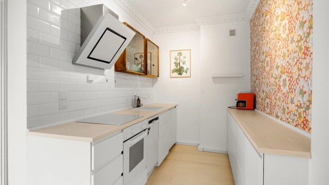 Hyggelig kjøkken som er innredet med glatte skapfronter og benkeplate i laminat med trestruktur og nedfelt kjøkkenvask i benkeplaten.