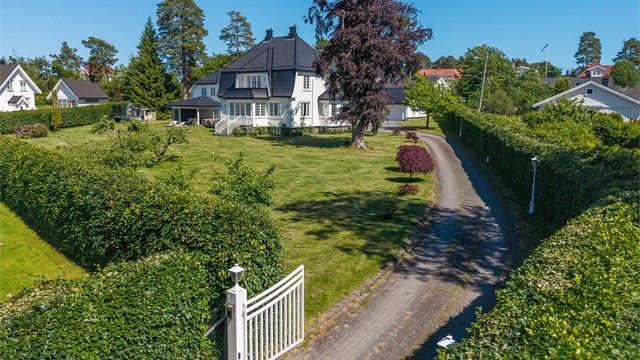 Eiendommen har adkomst via en privat oppkjørsel med elektriske porter, noe som gir både komfort, sikkerhet og en eksklusiv ramme rundt boligen som er omkranset av en flott bøkehekk.