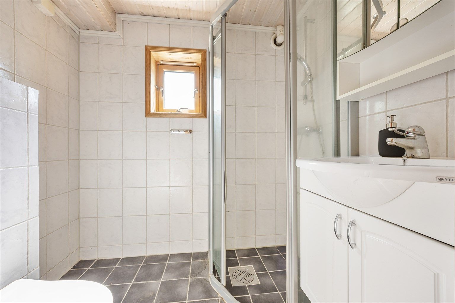 Badet i underetasjen er flislagt og utstyrt med dusj, servant og opplegg for vaskemaskin.