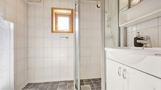 Badet i underetasjen er flislagt og utstyrt med dusj, servant og opplegg for vaskemaskin.