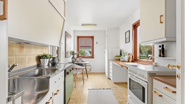 Praktisk kjøkken med laminatbenkeplate og oppvaskkum i rustfritt stål.