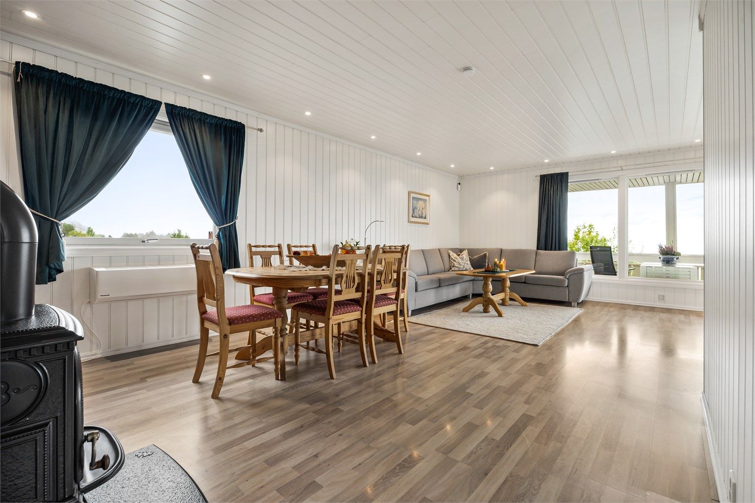 Lys vinkelstue med sofaområde og spiseplass.