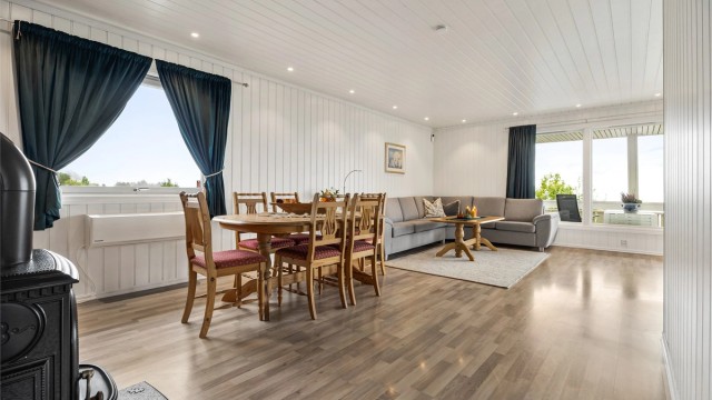 Lys vinkelstue med sofaområde og spiseplass.