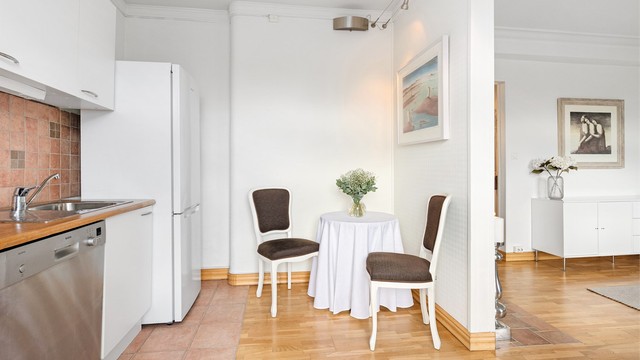 Kjøkkenet er utstyrt med frittstående hvitevarer og har fliser over benken.