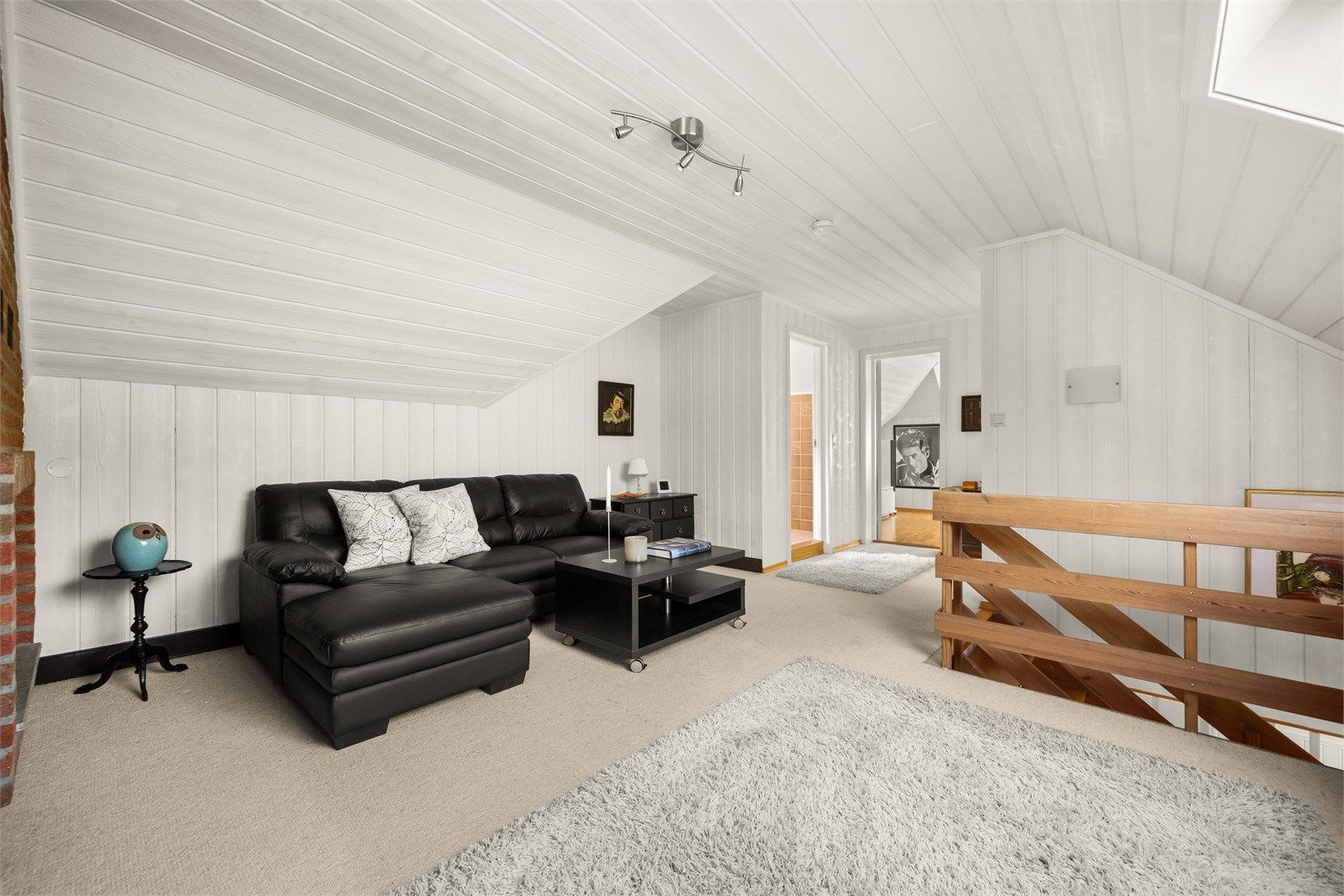 Loftstuen er et lunt og allsidig rom med vegg-til-vegg-teppe og malt panel.