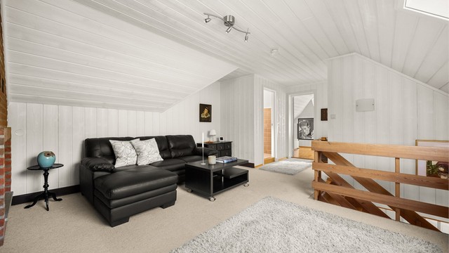 Loftstuen er et lunt og allsidig rom med vegg-til-vegg-teppe og malt panel.
