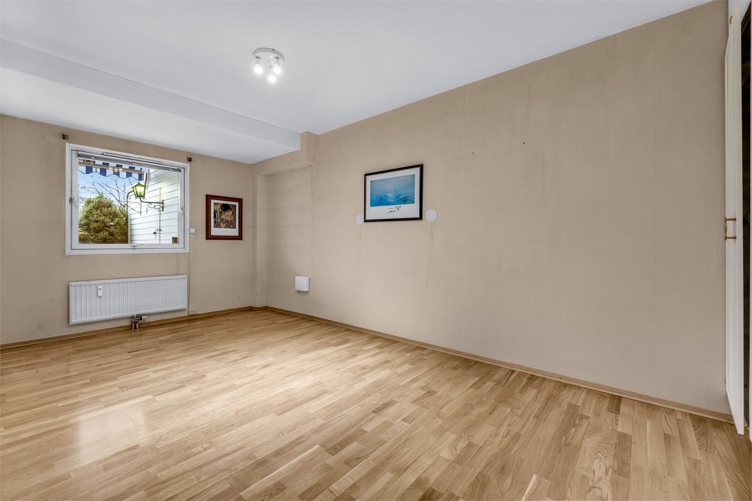 Stort soverom med pen parkett på gulv og vegger med behov for overflatebehandling.