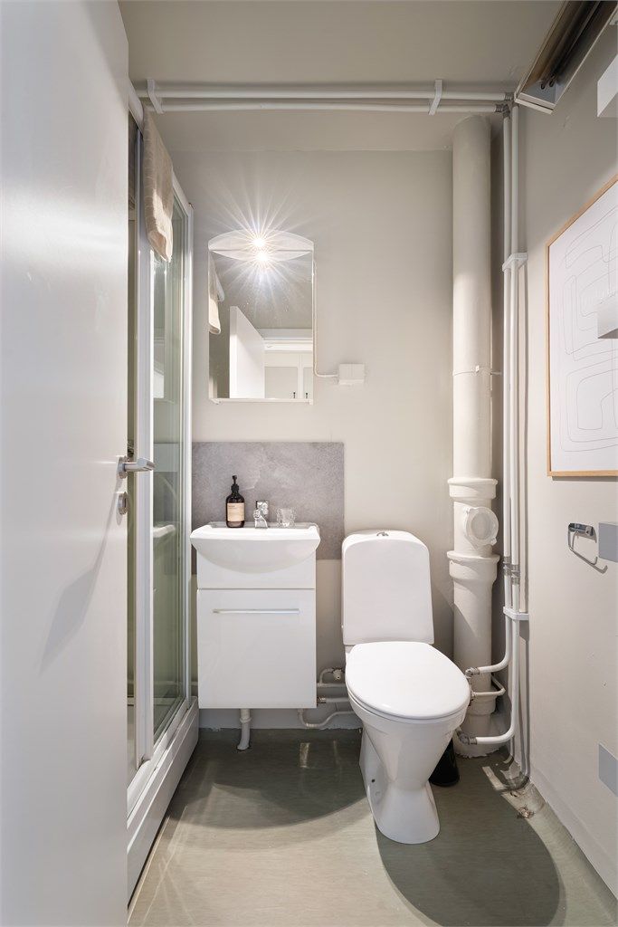 Badet har servant, speilskap med belysning, toalett og dusjkabinett. Rommet er funksjonelt i dag, men overflatene er av eldre dato. Det gir deg en fin mulighet til å pusse opp og skape et bad etter egen smak.