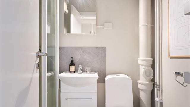 Badet har servant, speilskap med belysning, toalett og dusjkabinett. Rommet er funksjonelt i dag, men overflatene er av eldre dato. Det gir deg en fin mulighet til å pusse opp og skape et bad etter egen smak.