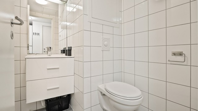 Dusjhjørne med forheng og vegghengt toalett