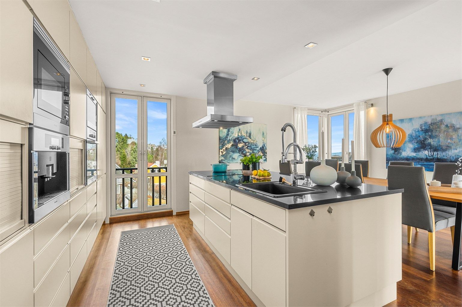 Kjøkkenet har en stilren og funksjonell utforming med plassbygde løsninger, kjøkkenøy og godt med skap- og benkeplass.