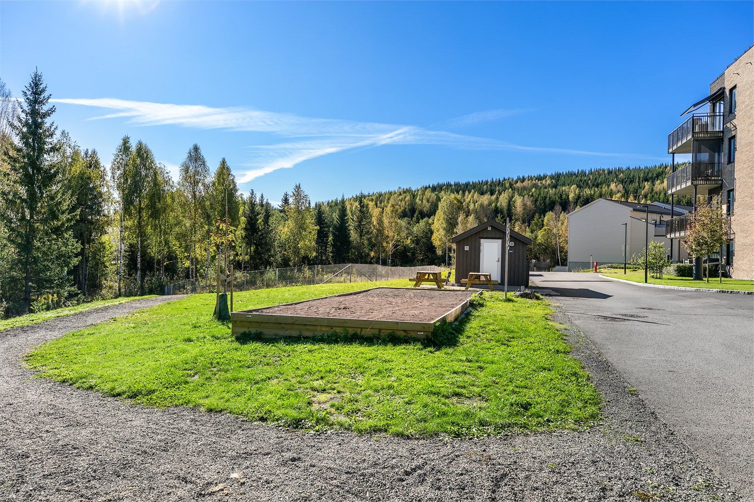 Asfalterte internveier og pent opparbeidede utearealer med beplantning. Her ser du bocciabanen.