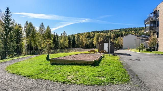 Asfalterte internveier og pent opparbeidede utearealer med beplantning. Her ser du bocciabanen.