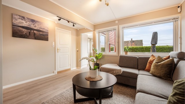 Store vindusflater slipper inn rikelig med dagslys, som sammen med det lyse laminatgulvet og de varme veggfargene gir en luftig og innbydende atmosfære, med fin utsikt mot den skjermede uteplassen.