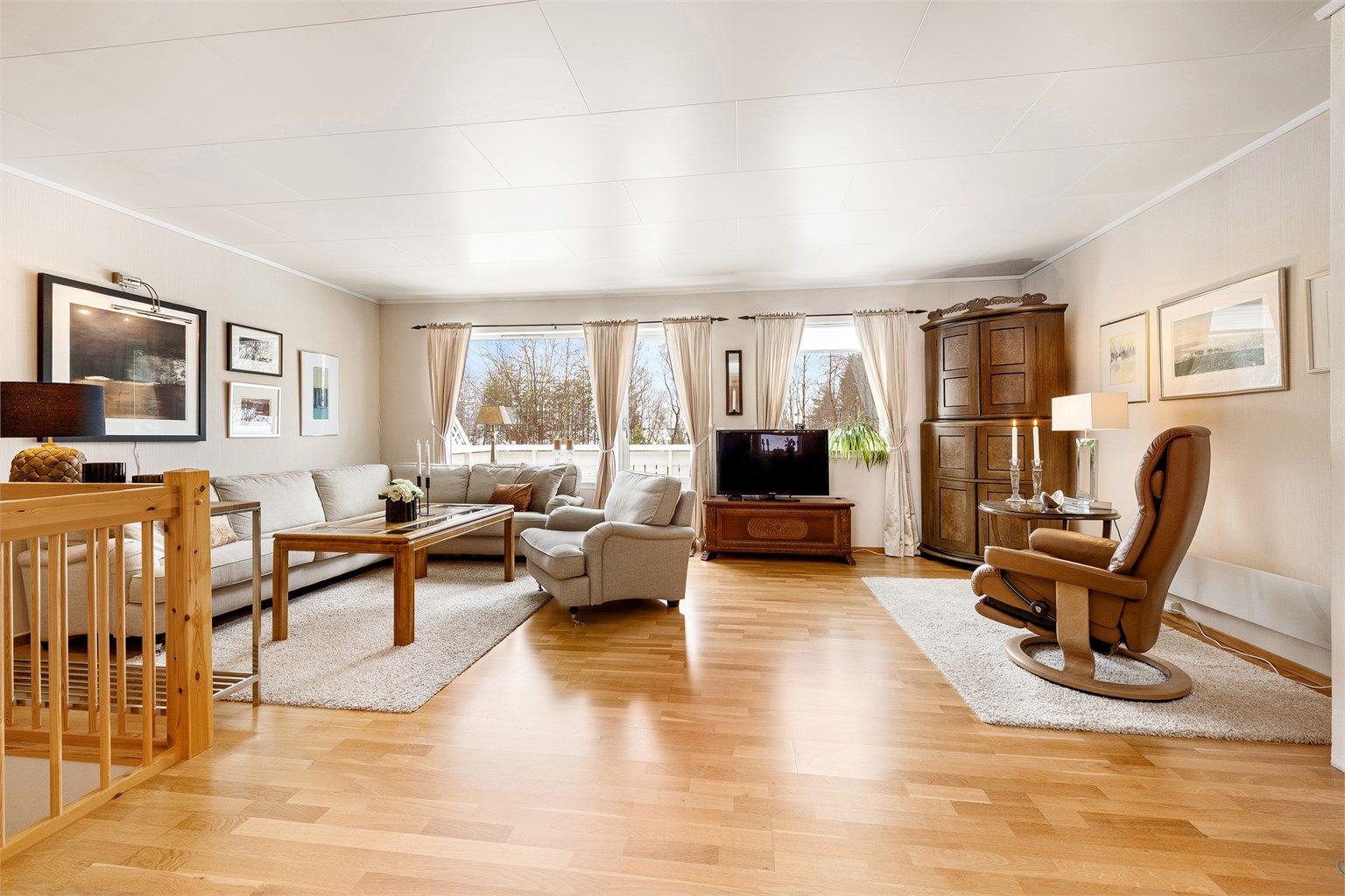 Den romslige stuen har store vindusflater og gjennomgående parkett på gulvet.