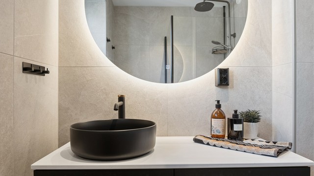 Rommet har flislagte overflater med gulvvarme og er innredet med vegghengt servantinnredning, speil med belysning, dusjhjørne og vegghengt toalett.