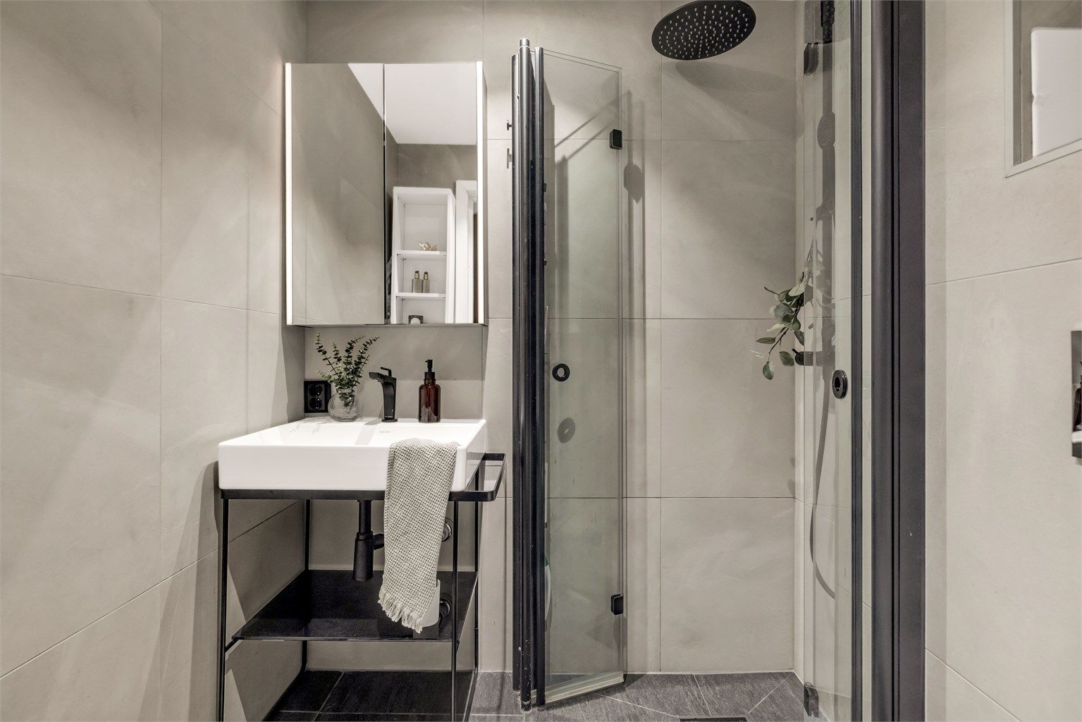 Badet er innredet med vegghengt toalett og egen dusjsone med innfellbare glassdører. Dusjen er tilkoblet både hånd- og regndusj.