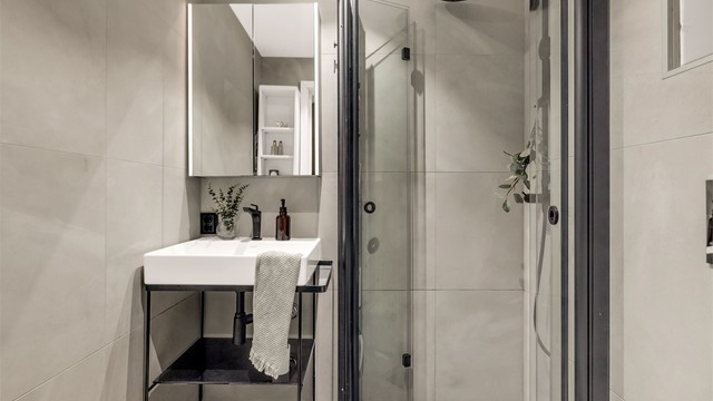 Badet er innredet med vegghengt toalett og egen dusjsone med innfellbare glassdører. Dusjen er tilkoblet både hånd- og regndusj.