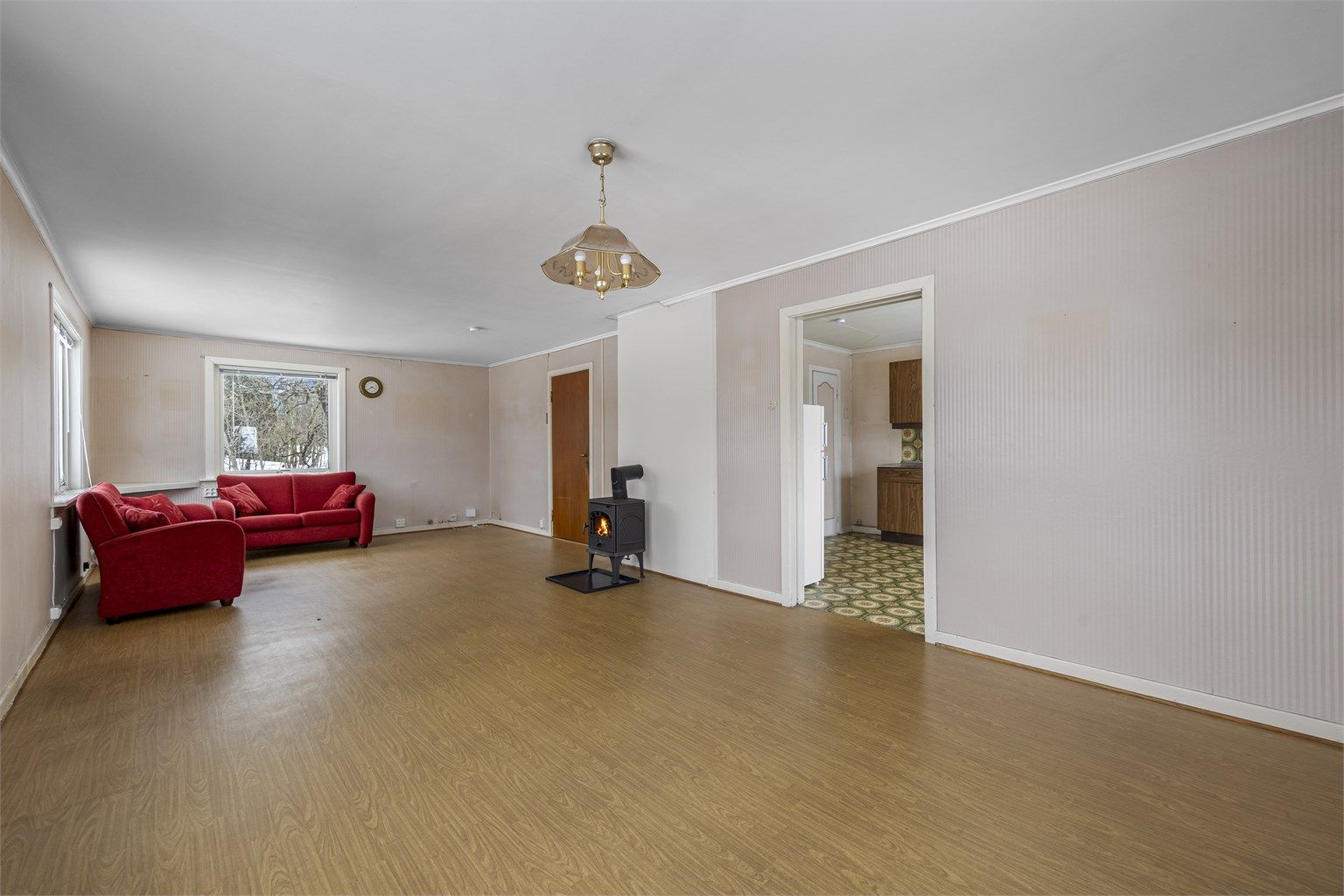 Rommet har gulvbelegg, tapetserte flater og panel på veggene.