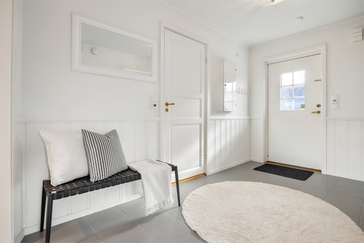 Romslig entré med flislagt gulv og gulvvarme.