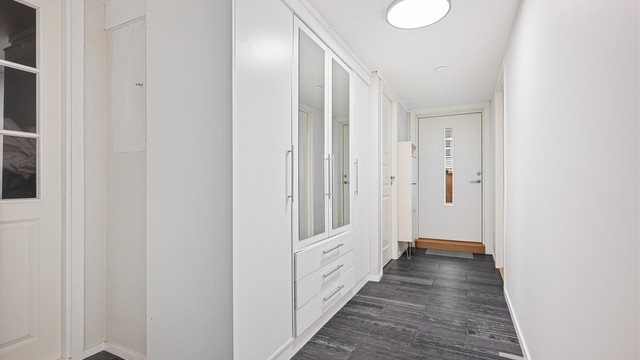 Hybel: Romslig entré med fliser på gulv, lyse veggflater og himling. Det er flere garderobeskap som gir rikelig med oppbevaringsplass.