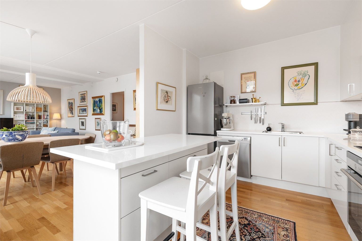 Lyst og fint kjøkken med øy og åpen løsning mot spisestuen og stuen.