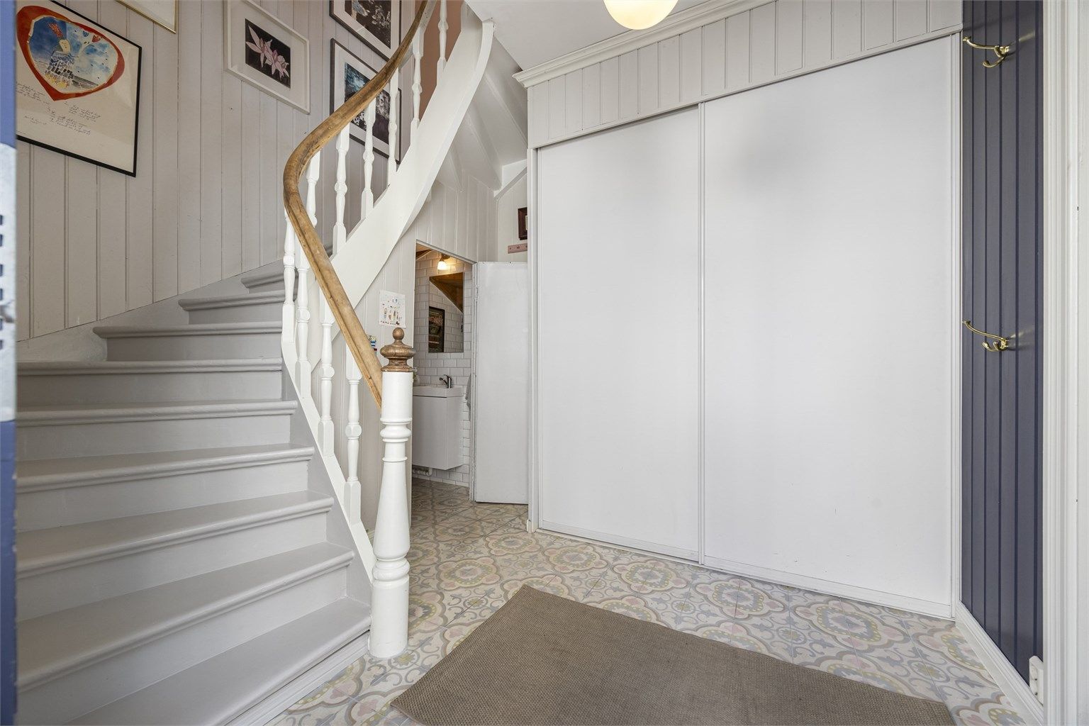 Hallen har en malt tretrapp som leder opp til andre etasje, samt en praktisk skyvedørsgarderobe.