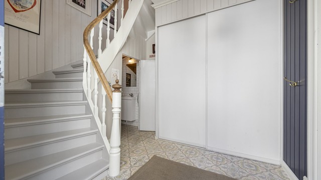 Hallen har en malt tretrapp som leder opp til andre etasje, samt en praktisk skyvedørsgarderobe.