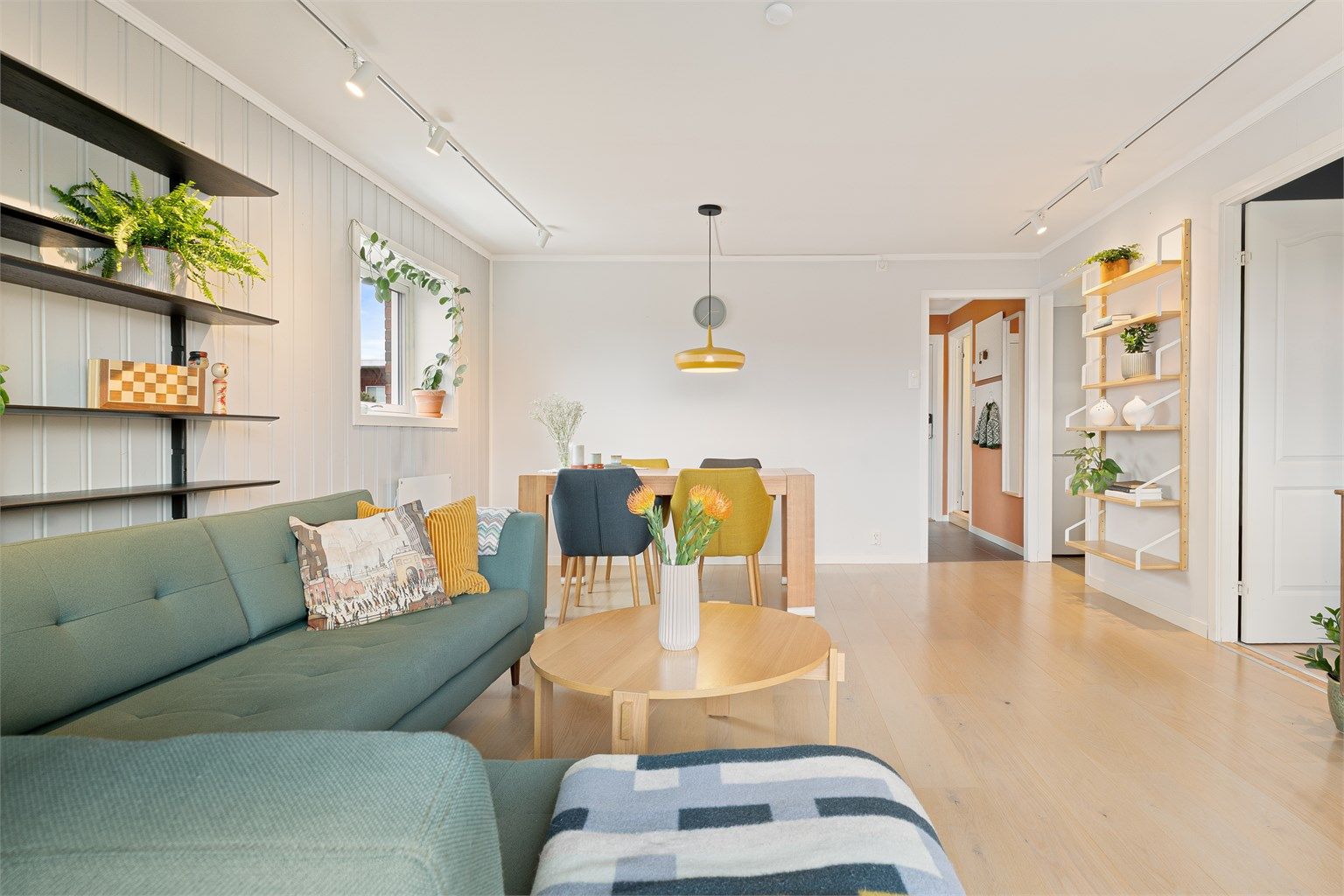 Gjennomgående parkettgulv og malte panelvegger skaper en helhetlig og lys atmosfære.