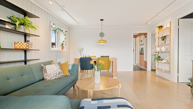 Gjennomgående parkettgulv og malte panelvegger skaper en helhetlig og lys atmosfære.