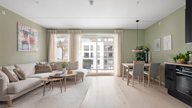 Stuen har store vindusflater som slipper inn godt med naturlig dagslys, kombinasjonen med det lyse 1-stavs parkettgulvet og de duse grønnmalte veggene gir god romfølelse