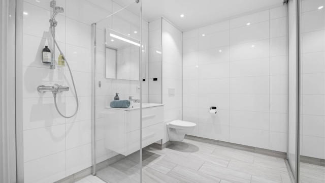 Baderom med vaskerom bak skyvedør med speil.