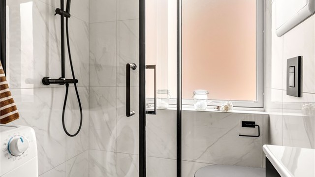 Badet har en gjennomgående stilig finish med detaljer som sort vegghengt toalett og innsvingbare dusjdører i glass med sorte detaljer.