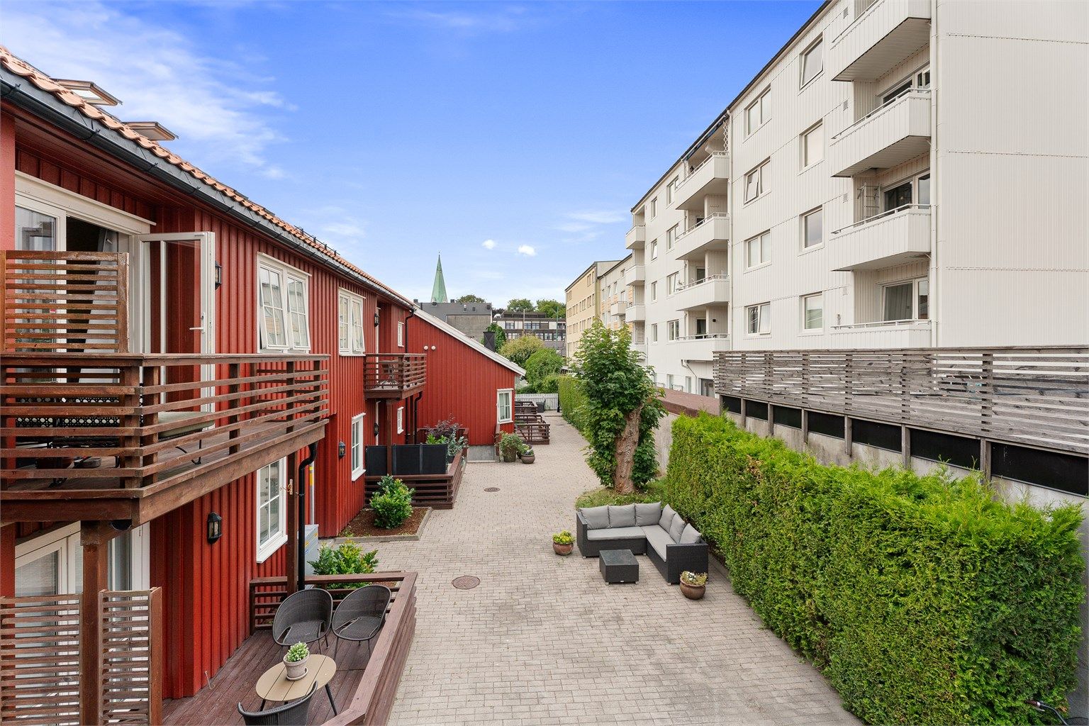 Skjermet og opparbeidet fellesareal omkranset av grønne hekker og trivelige fasader.