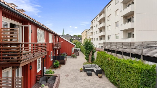 Skjermet og opparbeidet fellesareal omkranset av grønne hekker og trivelige fasader.