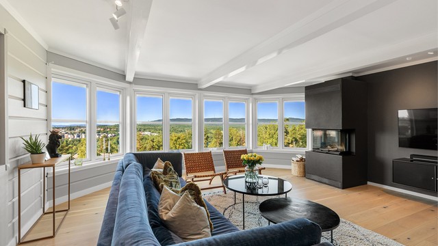 Den romslige stuen har en lun og innbydende atmosfære, med parkett på gulv, downlights og fine, synlige takbjelker